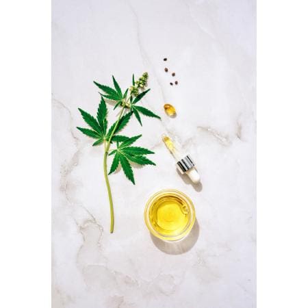 Marijauna leaf beside a bottle of face serum.