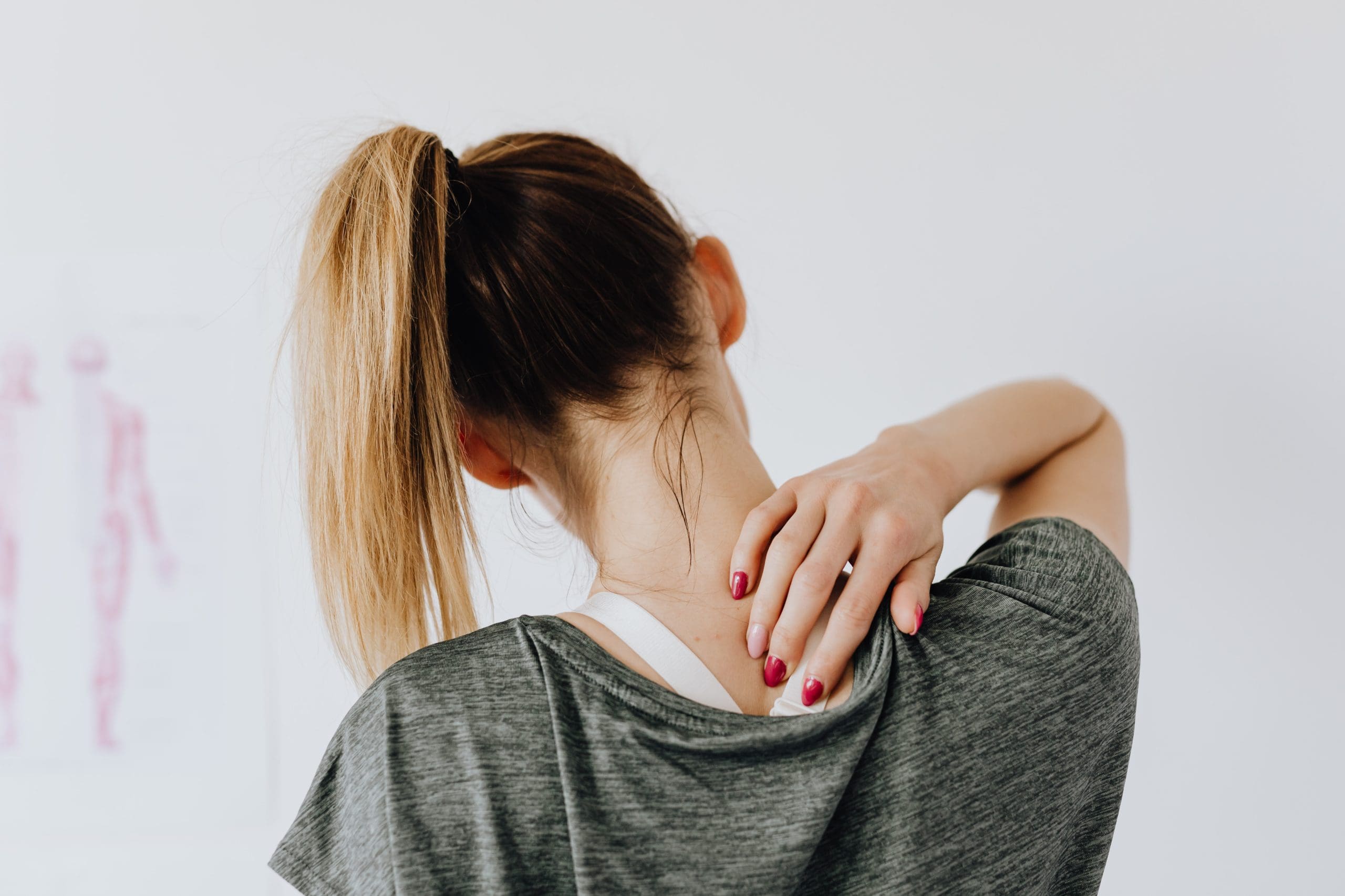 back-pain A woman with her back facing out, holding her neck in pain.